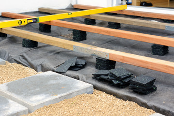 Unterkonstruktion für Terrasse mit Holzbalken und Terrassenpads aus Granulat und Bautenschutzmatte 