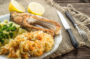 Fried fish, boiled potatoes and salad on rustic wooden background. Healthy meal.