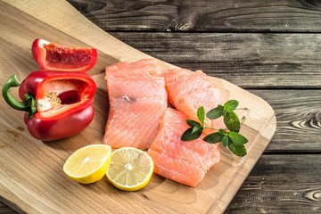 Fresh salmon fillets with lemon and paprika on wood, selective focus.