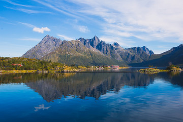 Fototapeta na wymiar Classic norwegian scandinavian summer landscape with mountains, fjord, lake and a church, with a blue sky, Norway, Lofoten Islands