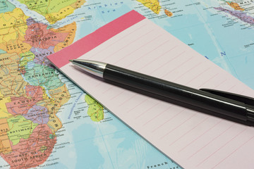 Notepad and pen on top of map