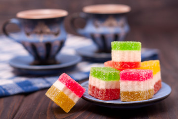 fruit jelly on wooden background with cup of tea
