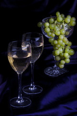 Glasses of wine and grapes on a dark background