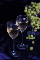 Glasses of wine and grapes on a dark background