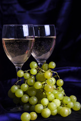 Glasses of wine and grapes on a dark background