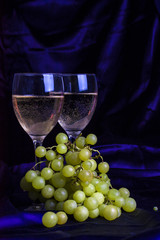 Glasses of wine and grapes on a dark background