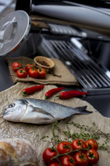High angle view of grilled and garnished whole fish on table surrounded by other dishes