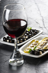 Copa de vino tinto con plato de aperitivos, aceitunas, anchoas y