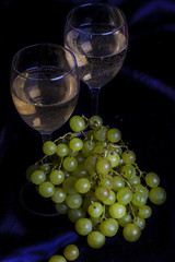 Glasses of wine and grapes on a dark background