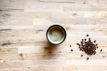 Obraz na płótnie Canvas espresso coffee in a blue cup and some coffee grain on a raw oak table