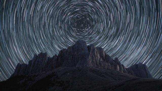 Beautiful star trails time-lapse over the rocky mountains. Polar North Star at the center of rotation. 4K resolution.