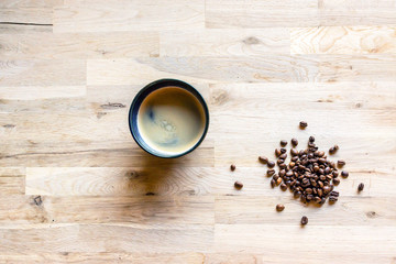 espresso coffee in a blue cup and some coffee grain on a raw oak table