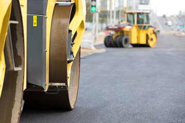 Road rollers vibration machines compacting fresh asphalt during construction roadworks