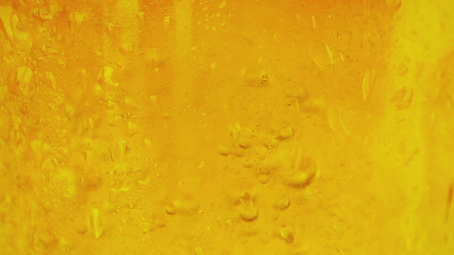 close-up of fresh beer with foam into glass as background