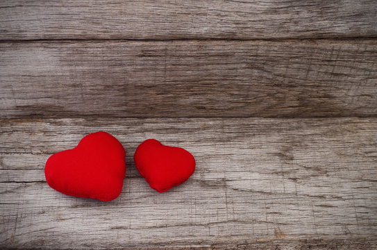 Two red hearts on wooden background.