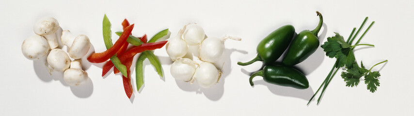 Mushrooms, peppers, jalape–o pepper, white onions and coriander against white background.