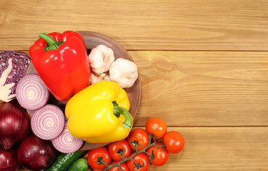 The composition of a set of fresh vegetables: peppers, tomatoes, onions, cucumber and garlic, which lie on an old rustic table. To design a cooking recipe or menu