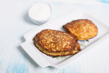 Potato pancakes with meat and sour cream in Belarusian style on light background