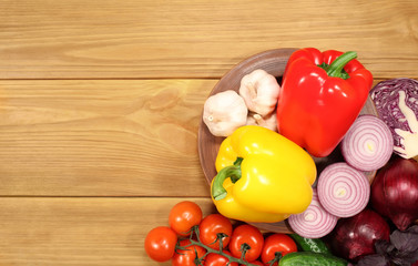 The composition of a set of fresh vegetables: peppers, tomatoes, onions, cucumber and garlic, which lie on an old rustic table. To design a cooking recipe or menu