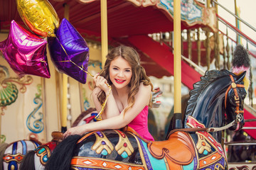 Fototapeta na wymiar Beautiful young girl on a merry go round