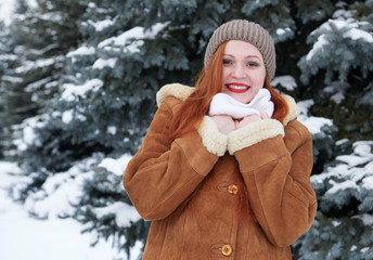 Happy young woman at winter and snowy fir trees