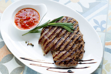 Delicious fried steak with sauce and spices on a white plate