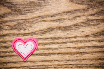 Pink fiber heart on wooden surface.