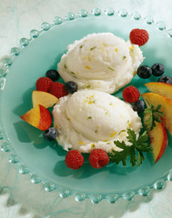 Lemon sorbet with berries and peaches served in plate.