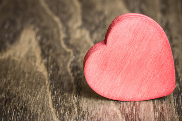 Single red wooden heart on wood.