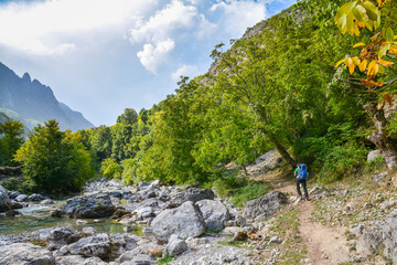 Tourist walking on the footpath along the river in the mountains