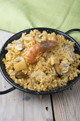 Vegetable paella with seafood on a wooden background