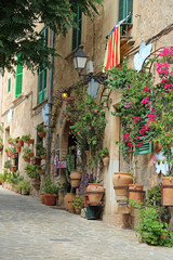 Üppiger Blumenschmuck an den Fassaden in einer alten Gasse von Valldemossa, Mallorca