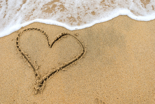 Heart drawn on sand of beach 