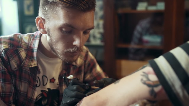 Portrait of tattoo artist making tattoo, close up
