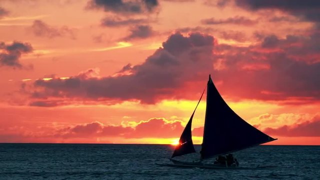 Amazing colors of tropical sunset. Sail boats silhouettes floating on ocean horizon. Boracay island, Philippines summer vacation