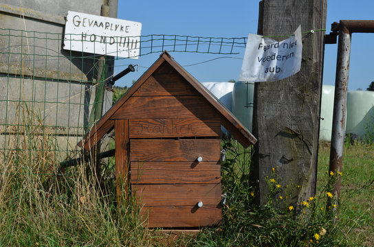 Wooden doghouse in a garden with signs beware the dog