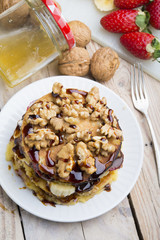 Pancakes with banana , walnut & chocolate on wood background