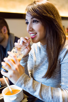 Beautiful young woman drinking orange juice in the restaurant