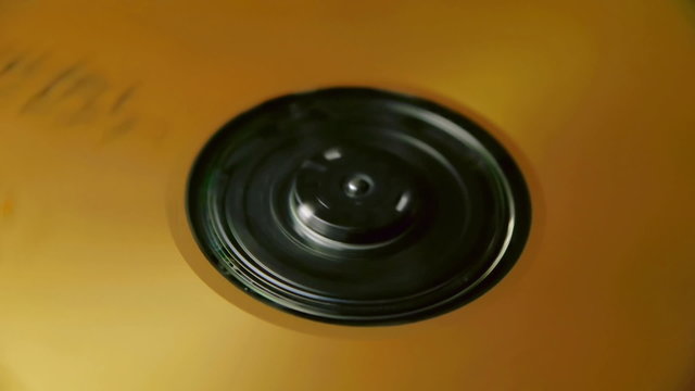 CD with golden tones spinning fast inside player Loop Video.