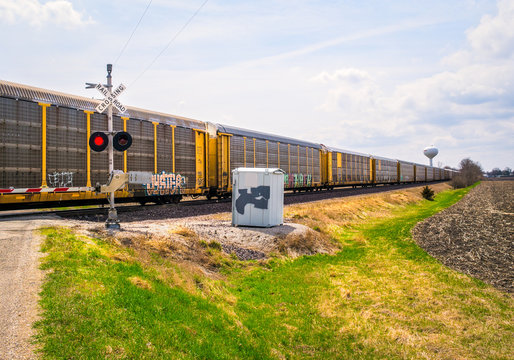 Wide angle view of freight train passing at railroad grade crossing with signal