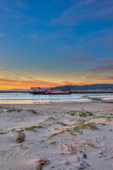 Portrait view of dredge barge and pipeline in the harbor beyond the sand dunes.