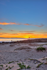 Fototapeta na wymiar Portrait view of sunset on camera right behind beach jetty.