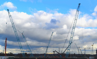 Construction site with tall industrial cranes and clouds in background