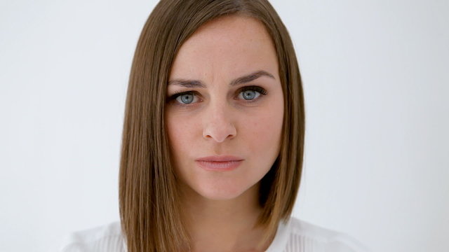 Woman, out of focus at background, comes to focus walking and stands with a disgusted gesture