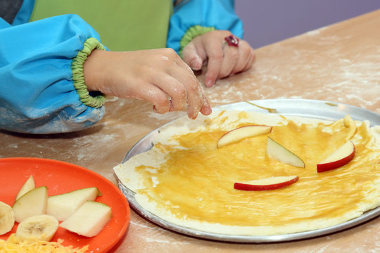 child preparing fruit pizza closeup