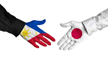 Philippines and Japan leaders shaking hands on a deal agreement - 102478229