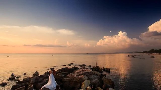 Stone Beach and Fisherman Silhouette at Sunset against Village