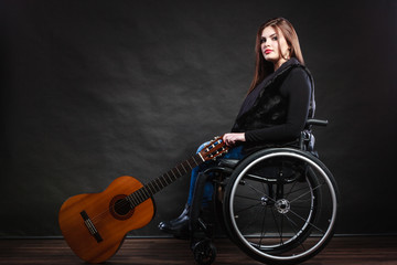 Obraz na płótnie Canvas Woman invalid girl on wheelchair with guitar