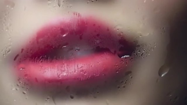 Close up of pink female lips kissing misted glass