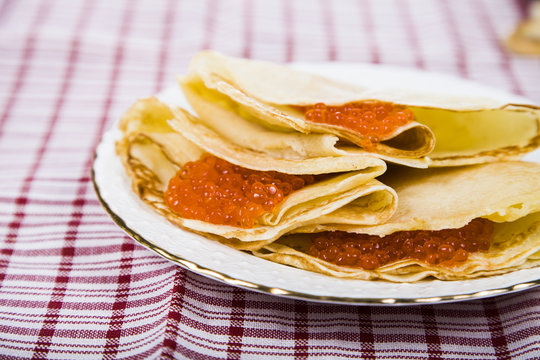 Pancakes with red caviar on a table.